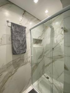 baño con ducha y puerta de cristal en Apartamento Av. Atlântica, com vista mar., en Balneário Camboriú