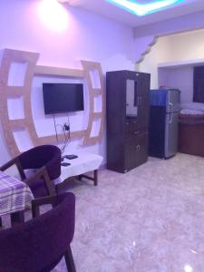 uma sala de estar com uma televisão, uma secretária e cadeiras em R mansion em Calangute
