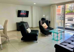 麥德林的住宿－Perfect 3BR Apartment Medellin best location，客厅配有两把椅子和电视