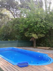 una piscina azul en una terraza de madera en Cabañas Los Cardales en Chascomús