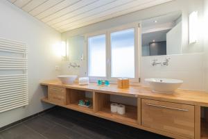 une salle de bain avec deux lavabos et un grand miroir dans l'établissement The Glacier Express Apartment - GRINDELHOMES, à Grindelwald 32 autres photos