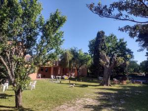 un parque con sillas blancas, mesas y árboles en Cabañas Los Cardales en Chascomús
