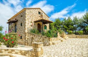 a stone house with a stone wall and flowers at Joanna's Stone Villas in Vasilikos