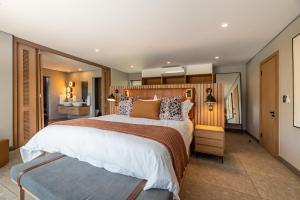 - une chambre avec un grand lit et une tête de lit en bois dans l'établissement Bakubung Villas, à Pilanesberg