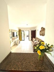 a living room with a couch and a vase of flowers at Guinea Apartment in Playa del Ingles