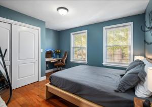 Colorful, Comfy & Modern - Close to NYC - Parking! في Mount Vernon: غرفة نوم بجدران زرقاء وسرير ومكتب