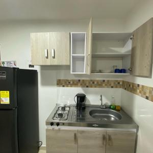 a kitchen with a sink and a black refrigerator at Elegante Apartaestudio NUEVO en Cali Champagnat in Cali