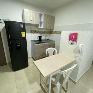 a small kitchen with a black refrigerator and a table at Elegante Apartaestudio NUEVO en Cali Champagnat in Cali