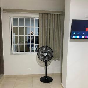 a fan in a room with a window at Elegante Apartaestudio NUEVO en Cali Champagnat in Cali