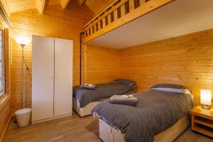 two beds in a room with wooden walls at Spacious Log Cabin with Parking near Cambridge in Cambridge