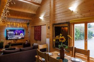 a living room with a table and a couch and a television at Cosy Log Cabin with Parking near Cambridge in Cambridge