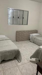 een slaapkamer met 2 bedden en een tegelvloer bij Casa Califórnia in Lindóia