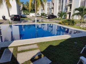ein Swimmingpool vor einem Gebäude mit Palmen in der Unterkunft Departamento equipado muy cerca de Playa in Manzanillo
