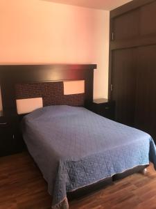 a bedroom with a bed with a blue comforter at Cómodo departamento cerca de Playa Miramar in Manzanillo