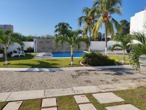 a resort with a swimming pool and palm trees at Cómodo departamento cerca de Playa Miramar in Manzanillo