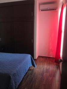 a bedroom with a bed and a red wall at Cómodo departamento cerca de Playa Miramar in Manzanillo +8 photos