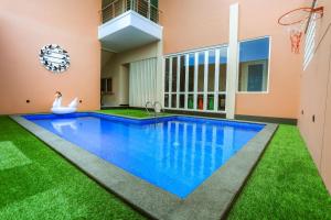 una piscina en una casa con césped verde en The Horizontal Hotel Pacitan, en Pacitan