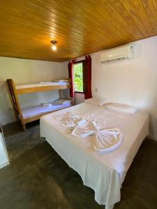 a bedroom with a large bed with white sheets at Eco Pousada Mentawai in Itacaré