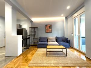 uma sala de estar com um sofá azul e uma mesa em Osiris Hideaway Inn, Kerameikos, Athens, Industrial 2-br apt, balconies & Netflix em Atenas