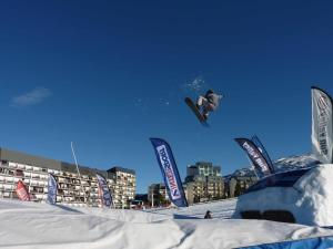 un hombre volando por el aire mientras monta una tabla de snowboard en Studio Moderne au pied des pistes 4 Pers - La Pierre Saint-Martin GR10, en Arette