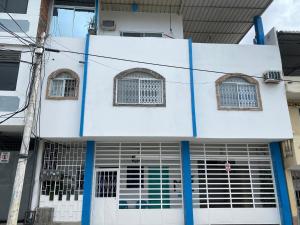 un edificio blanco con columnas y ventanas azules en Beautiful apartment near Malecon and Murcielago beach!, en Manta