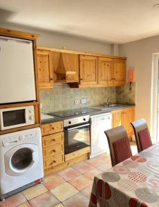 - une cuisine avec des placards en bois et un lave-vaisselle blanc dans l'établissement The Robins Rest, à Killarney