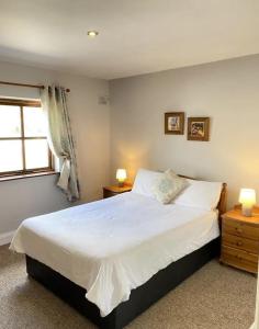 een slaapkamer met een groot wit bed en een raam bij The Robins Rest in Killarney
