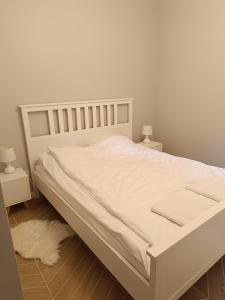 a white bed in a bedroom with two night stands at Apartament Ustrońska Jodełka z Sauną-Nadrzeczna in Ustroń