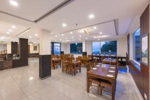 un ristorante con tavoli e sedie in legno e finestre di Stone Wood Mountain Resort, Dharamshala a Dharamshala