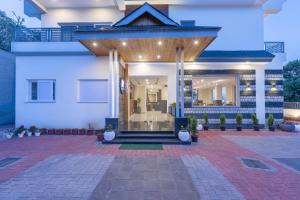 a white house with a front entrance with potted plants at Stone Wood Mountain Resort, Dharamshala in Dharamshala