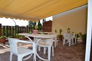 a patio with white tables and white chairs at Pension Vergina in Vergina