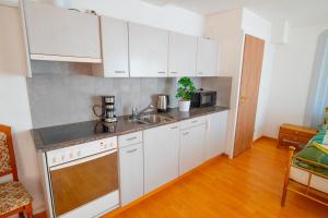 a kitchen with white cabinets and a sink at Residence Villa Flora in Interlaken