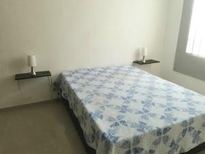 um quarto com uma cama com um cobertor azul e branco em Precioso apto con un aire acondicionado en la Sala em Ricaurte
