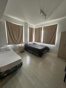 1 dormitorio con 2 camas y 2 ventanas en Mis Vacaciones en Buenos Aires
