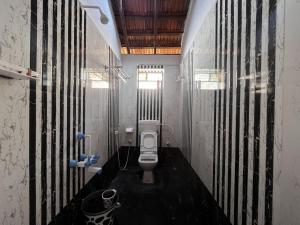 - une salle de bains avec toilettes dans une chambre dotée de murs en bois dans l'établissement Revibe Beach Hostel Gokarna, à Gokarna
