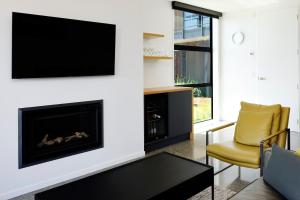 a living room with a fireplace and a tv at Harakeke Boutique Accommodation in Mahana