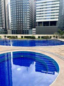 duży niebieski basen z wysokimi budynkami w tle w obiekcie Fort Bonifacio BGC condo w mieście Manila