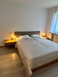 een slaapkamer met een groot wit bed met 2 lampen bij Apartment - Über den Wolken in Batschuns