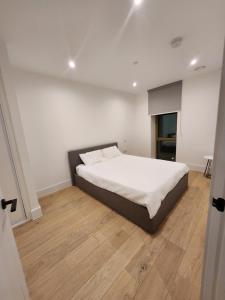 a bedroom with a bed with white sheets and wooden floors at Stunning 2-Bed Apartment in Brentford in Brentford