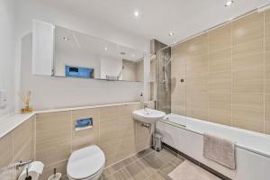 a bathroom with a toilet and a sink and a tub at Great 2 Bed Flat With City View in London