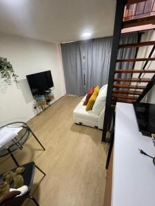 Mini Loft en Coyoacán في مدينة ميكسيكو: غرفة معيشة مع أريكة بيضاء وتلفزيون