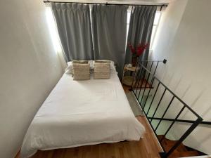 uma cama com lençóis brancos e almofadas num quarto em Mini Loft en Coyoacán em Cidade do México
