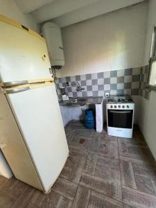 Il comprend une cuisine équipée d'un réfrigérateur blanc et d'une cuisinière. dans l'établissement Casita sencilla a cuatro cuadras del mar, à La Aguada