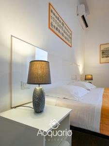 Acquario Suites في جينوا: غرفة نوم بسرير ومصباح على طاولة