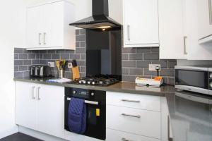 cocina con armarios blancos y fogones en Glasgow, Bothwell, 3 bed, Suitable for Long Stays en Bothwell