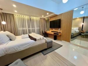 Hotel Vibe Condo at Uptown Parksuites BGC في مانيلا: غرفة نوم بسرير ومكتب وتلفزيون