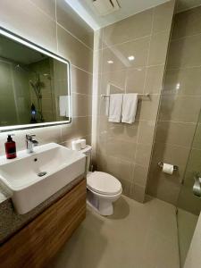 a bathroom with a sink and a toilet and a mirror at Hotel Vibe Condo at Uptown Parksuites BGC in Manila