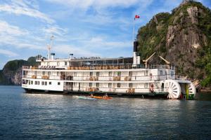 a large cruise ship on the water with a boat at Emeraude Classic Cruises in Ha Long