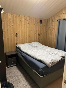 1 dormitorio con 1 cama y pared de madera en Malangen Arctic Sealodge Cabin 10, en Meistervik