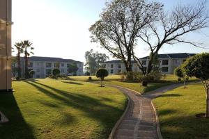 a brick path in a park with buildings in the background at La Casa De Made-Luxury Apartment-No loadshedding in Sandton